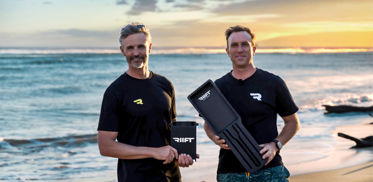 John and Al the founders of RIIFT, standing on a beach at sunset, each holding a RIIFT battery and RIIFT Tracks. 